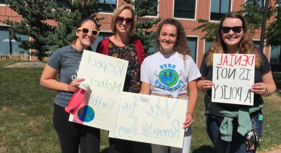 Student standing with signs about Climate